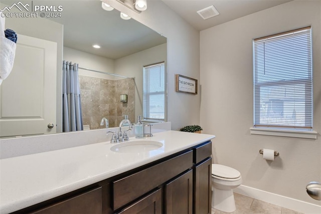 bathroom with tile patterned floors, vanity, a healthy amount of sunlight, and toilet