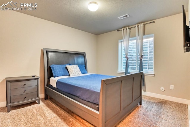 bedroom with a textured ceiling and light colored carpet