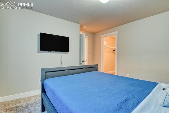 bedroom featuring carpet flooring, a spacious closet, a closet, and a textured ceiling