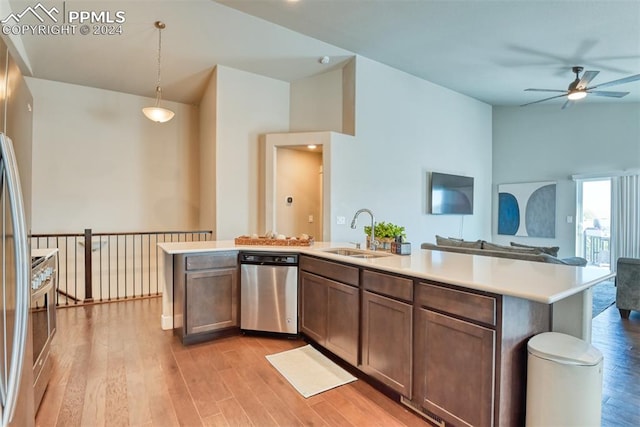 kitchen with sink, stainless steel appliances, decorative light fixtures, a center island with sink, and light wood-type flooring