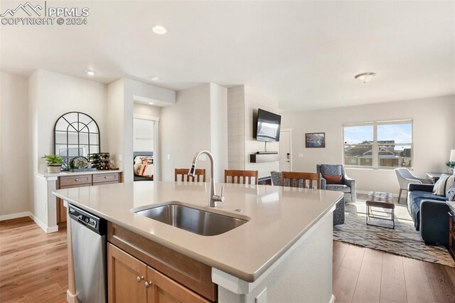 kitchen featuring dishwasher, light hardwood / wood-style floors, sink, and an island with sink