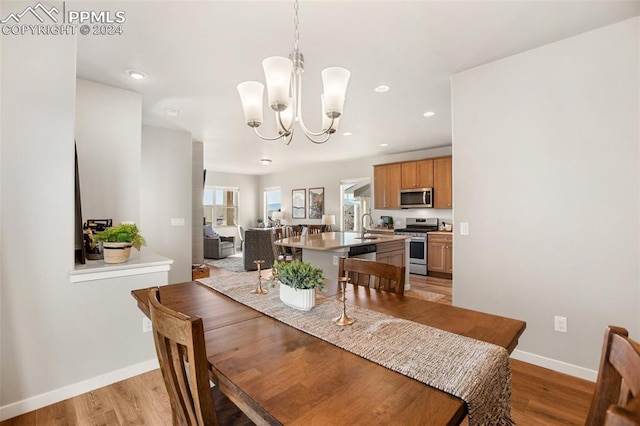 dining room with a chandelier, sink, and light hardwood / wood-style floors