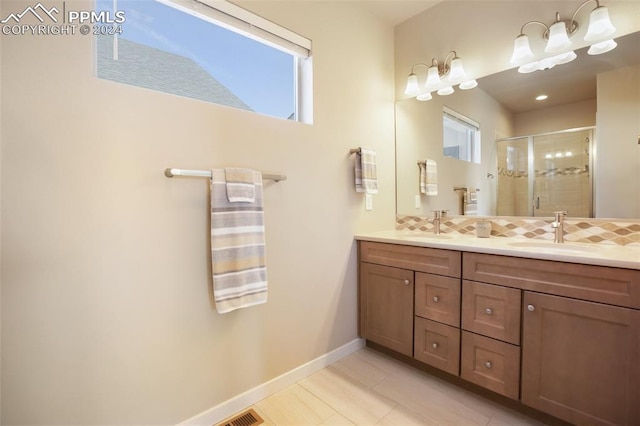 bathroom with tile patterned flooring, vanity, a healthy amount of sunlight, and a shower with shower door