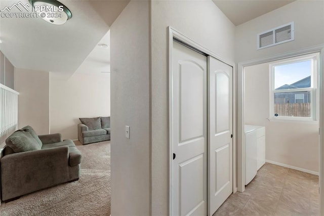 hall featuring washer and dryer and light carpet