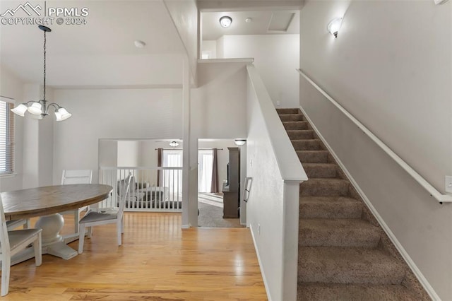 stairway with hardwood / wood-style floors, plenty of natural light, and a chandelier