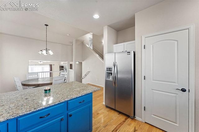 kitchen with pendant lighting, light hardwood / wood-style flooring, blue cabinetry, light stone counters, and stainless steel fridge with ice dispenser