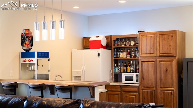 920 E 14th St, La Junta, CO 81050 - kitchen with decorative light fixtures, a kitchen breakfast bar, white appliances, and kitchen peninsula
