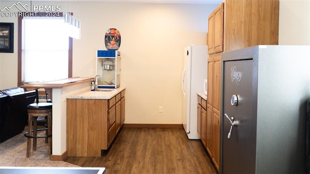 920 E 14th St, La Junta, CO 81050 - kitchen with sink, dark hardwood / wood-style floors, white fridge with ice dispenser, decorative light fixtures, and a kitchen bar