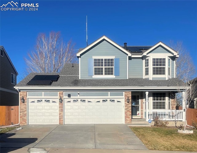 view of front of house with covered porch, a garage, and solar panels