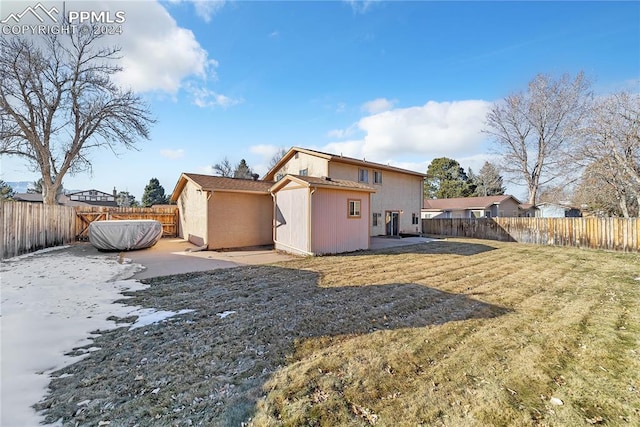 rear view of property with a yard and a storage unit