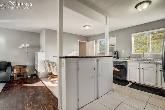 kitchen featuring light stone countertops, white cabinets, sink, light tile patterned floors, and dishwasher