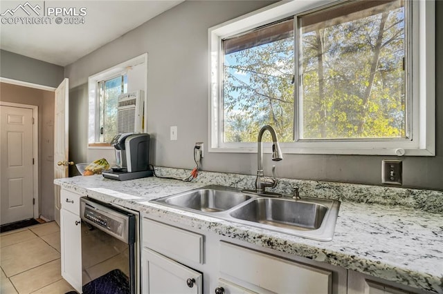 kitchen featuring sink, light tile patterned floors, an AC wall unit, dishwasher, and white cabinetry