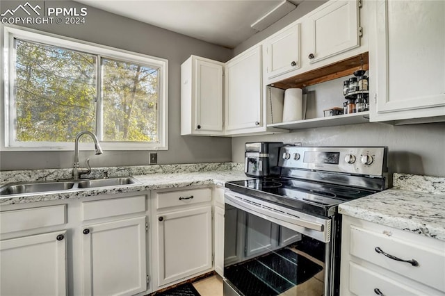 kitchen featuring white cabinets, stainless steel electric range, light stone countertops, and sink