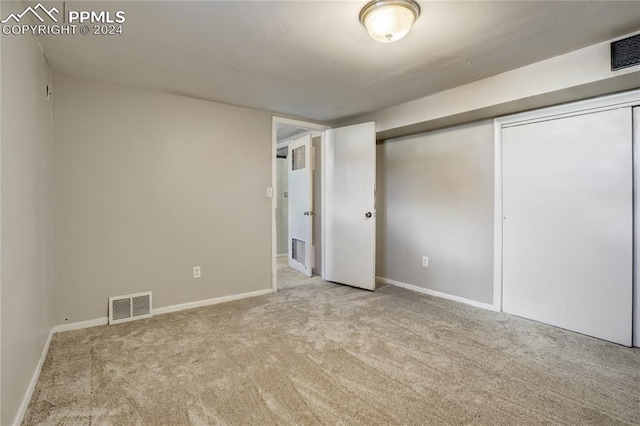 unfurnished bedroom featuring light carpet and a closet