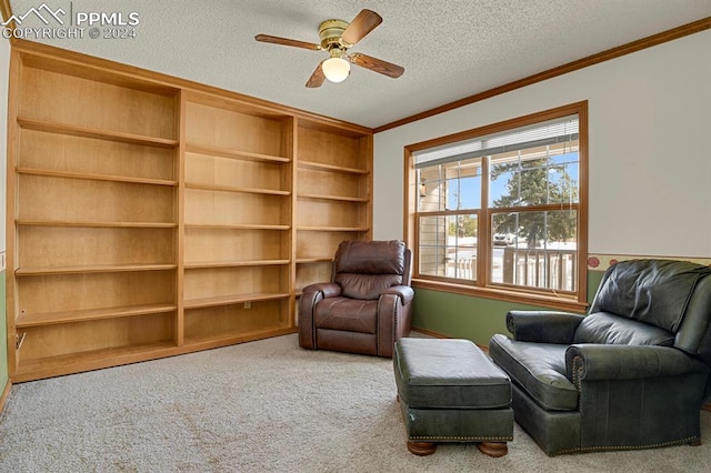 sitting room featuring ceiling fan, carpet floors, a textured ceiling, and ornamental molding