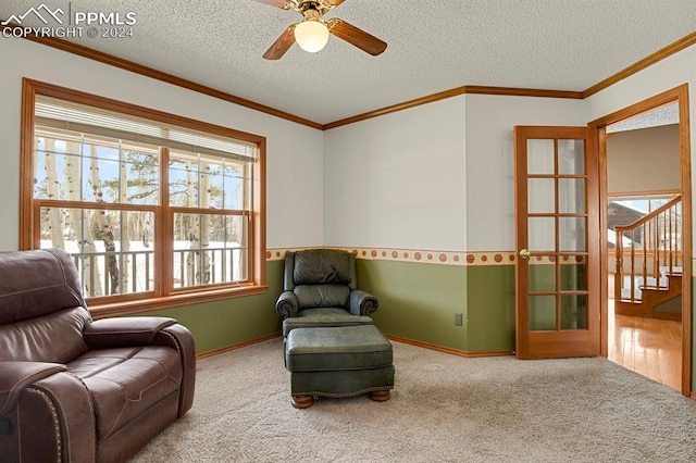 sitting room with carpet flooring, ceiling fan, crown molding, and a textured ceiling