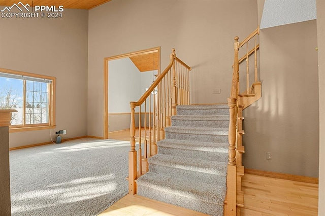 staircase with hardwood / wood-style flooring and high vaulted ceiling