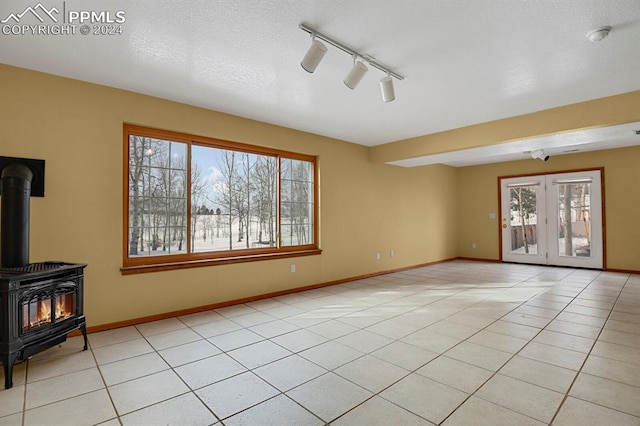 unfurnished living room featuring a wood stove, a wealth of natural light, and light tile patterned flooring