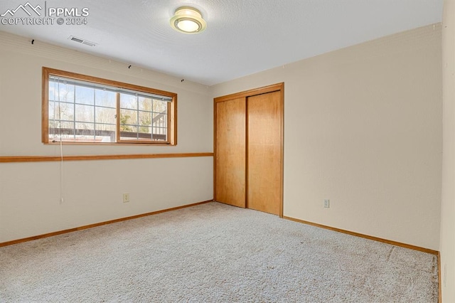 unfurnished bedroom with light carpet and a closet