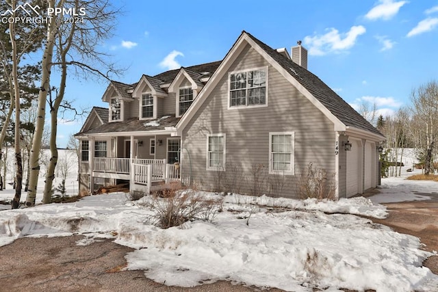 cape cod-style house featuring a garage and covered porch