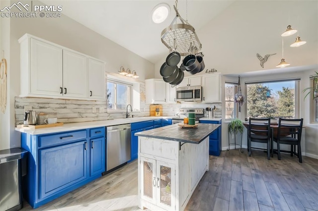 kitchen with blue cabinetry, a center island, stainless steel appliances, plenty of natural light, and decorative light fixtures