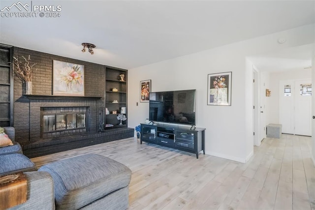 living room with light hardwood / wood-style floors, built in features, and a fireplace