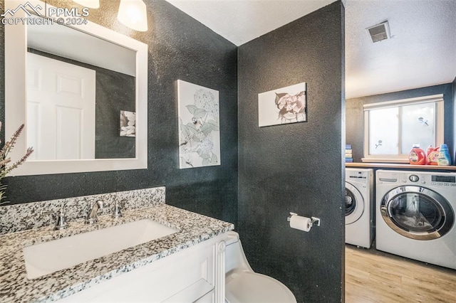 bathroom featuring washer and dryer, vanity, hardwood / wood-style flooring, and toilet