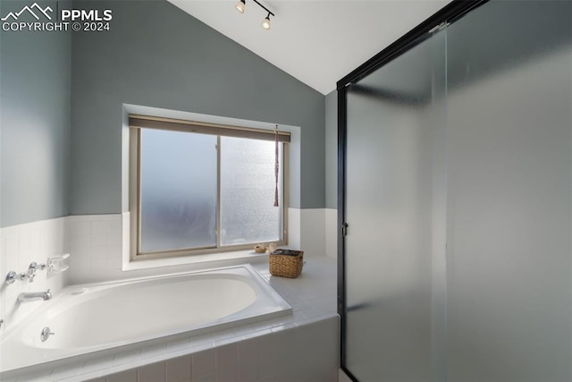 bathroom with lofted ceiling and tiled tub