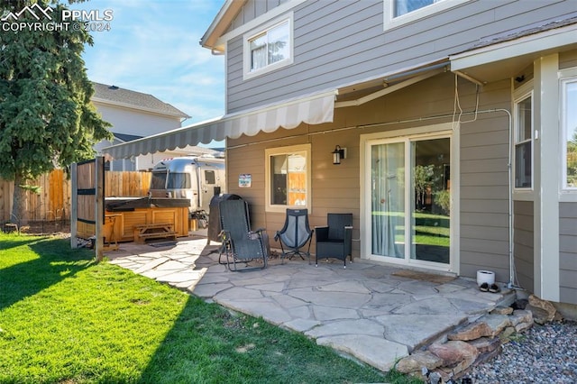 rear view of house featuring a yard, a patio, and a hot tub