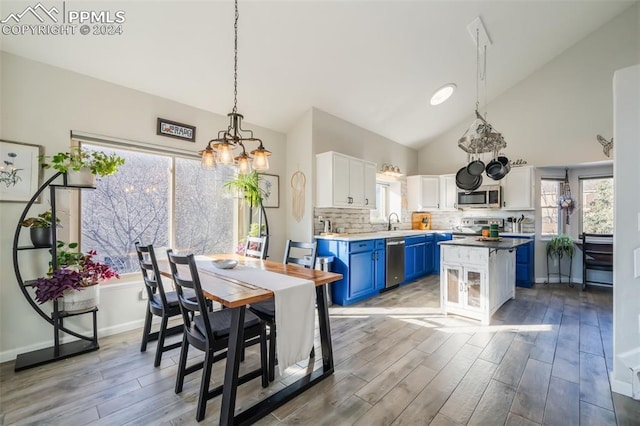 dining room with hardwood / wood-style floors, high vaulted ceiling, a chandelier, and sink