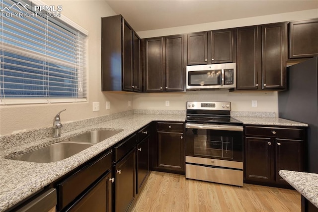 kitchen with dark brown cabinets, stainless steel appliances, light hardwood / wood-style floors, and sink