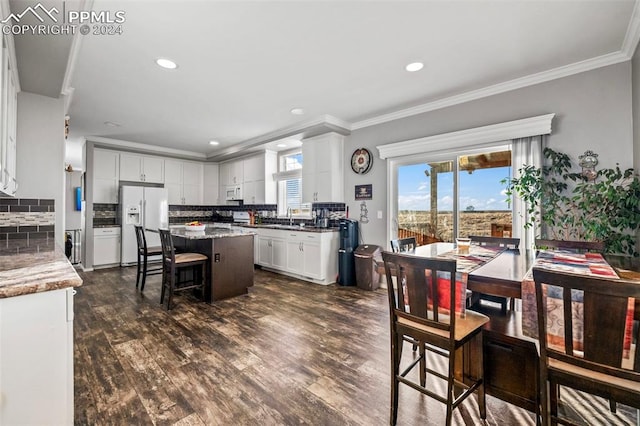 kitchen with a center island, dark wood-type flooring, white appliances, decorative backsplash, and white cabinets