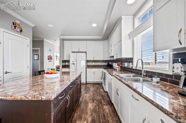 kitchen with sink, dark wood-type flooring, white appliances, a kitchen island, and ornamental molding