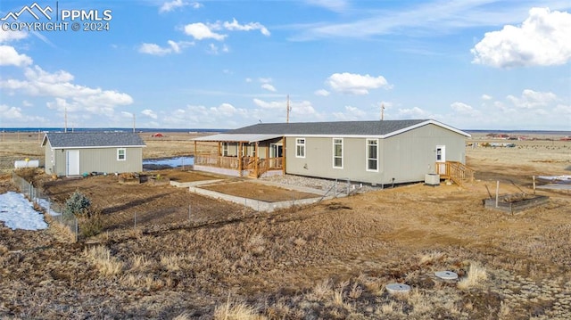 rear view of house with a rural view and a storage shed