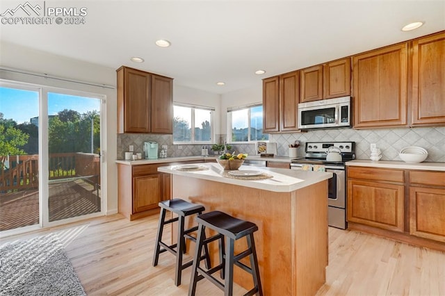 kitchen with a kitchen island, a healthy amount of sunlight, light wood-type flooring, and appliances with stainless steel finishes