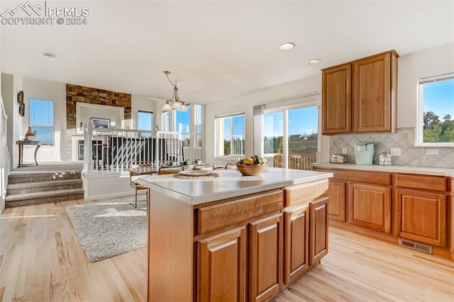 kitchen featuring a center island, hanging light fixtures, an inviting chandelier, tasteful backsplash, and light hardwood / wood-style floors