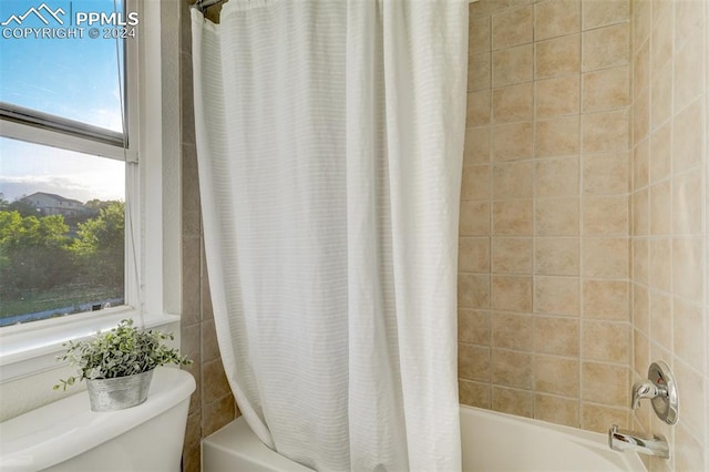 bathroom with toilet and shower / bath combo with shower curtain