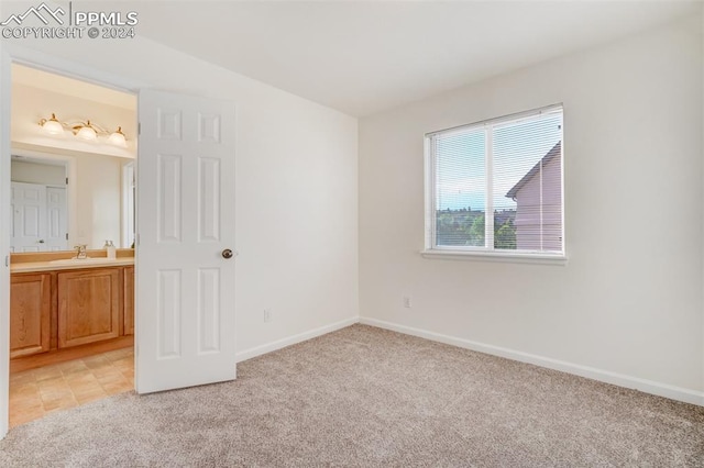 unfurnished bedroom with light carpet, sink, and ensuite bathroom