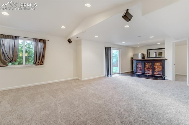 unfurnished living room featuring carpet flooring, plenty of natural light, and lofted ceiling