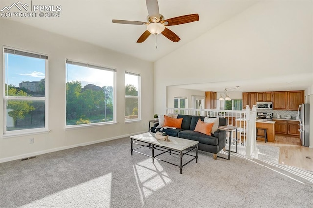 carpeted living room with ceiling fan and high vaulted ceiling