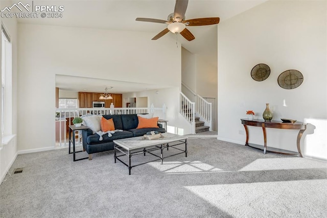 living room with light carpet, ceiling fan with notable chandelier, and high vaulted ceiling