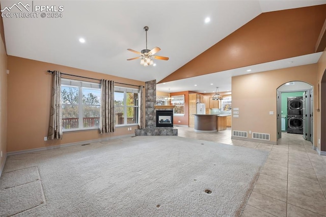 unfurnished living room featuring high vaulted ceiling, ceiling fan, stacked washer / drying machine, and light tile patterned flooring