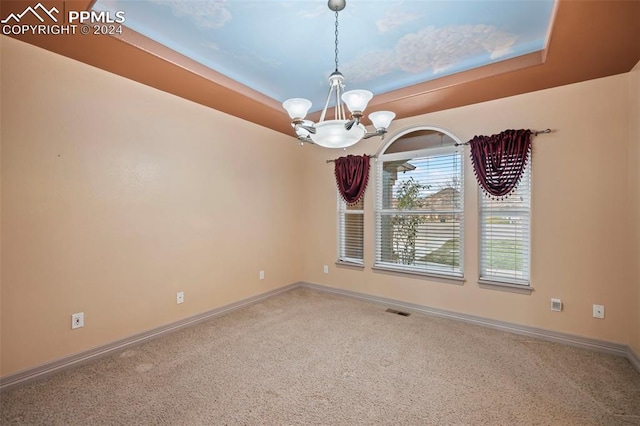 unfurnished room featuring a raised ceiling, carpet floors, and an inviting chandelier