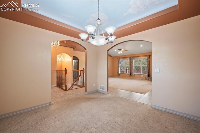 carpeted spare room featuring ceiling fan with notable chandelier