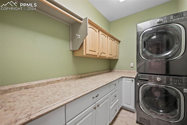 laundry area featuring light tile patterned floors, cabinets, and stacked washer and clothes dryer