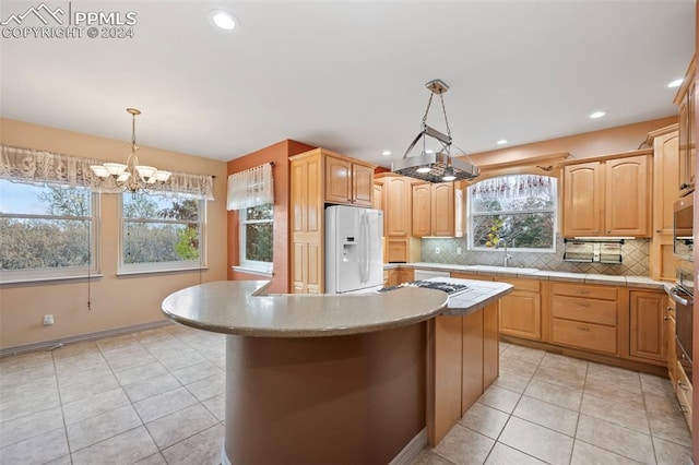 kitchen with sink, hanging light fixtures, an inviting chandelier, white refrigerator with ice dispenser, and a kitchen island