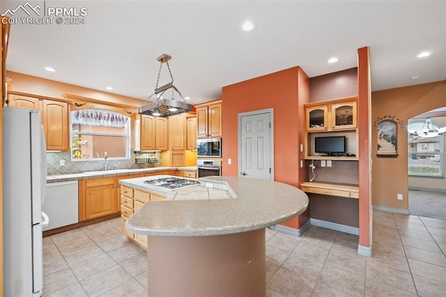 kitchen with pendant lighting, a wealth of natural light, a kitchen island, and appliances with stainless steel finishes