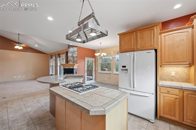 kitchen with stainless steel gas cooktop, white refrigerator with ice dispenser, pendant lighting, vaulted ceiling, and a kitchen island