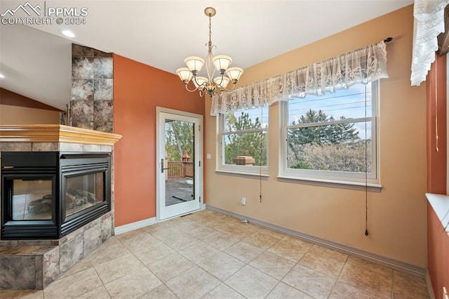 unfurnished dining area with light tile patterned flooring, a notable chandelier, and a tiled fireplace