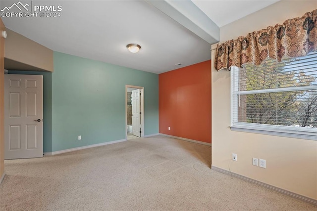 carpeted spare room with beamed ceiling